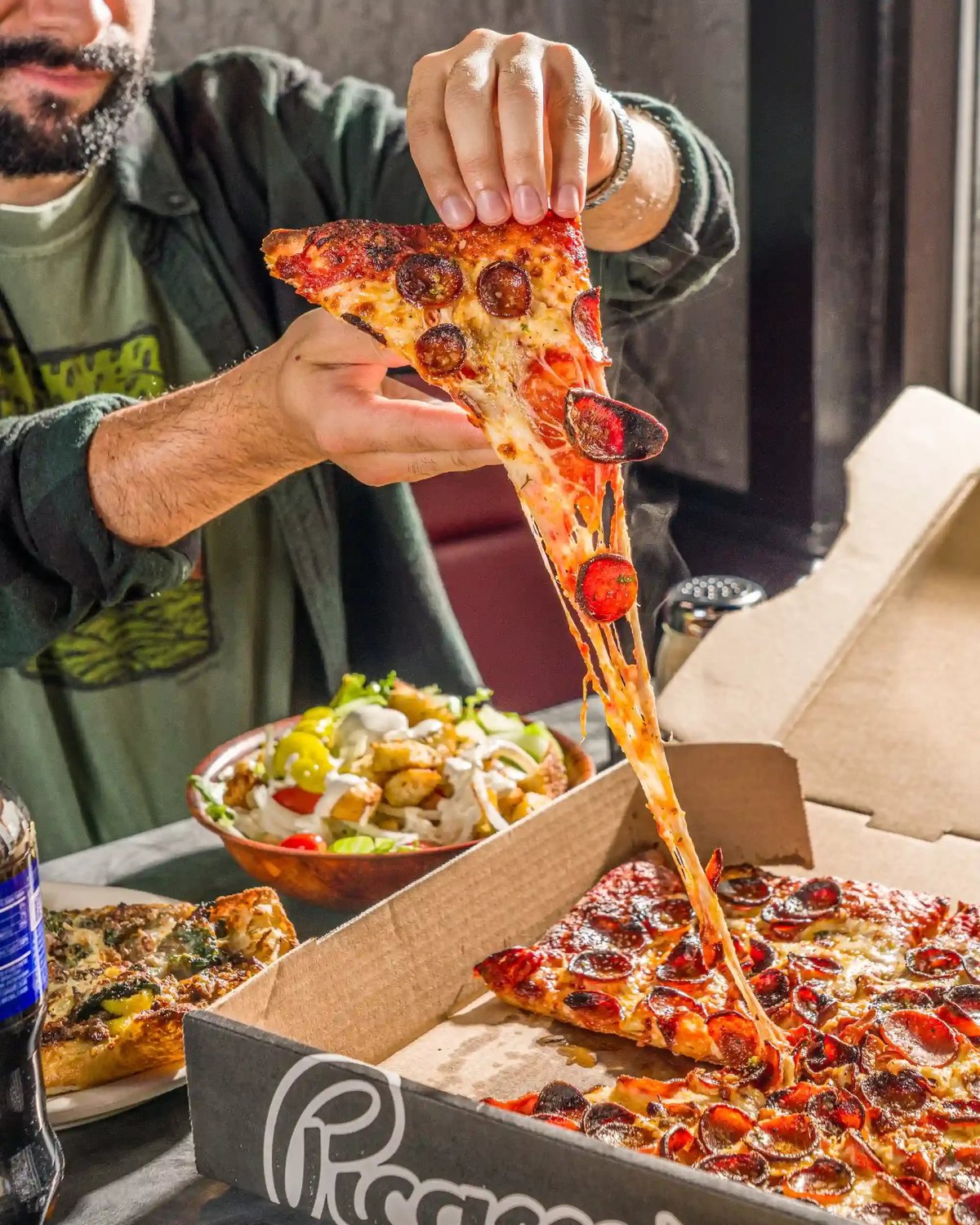 Person pulling a slice of Picasso's Pizza