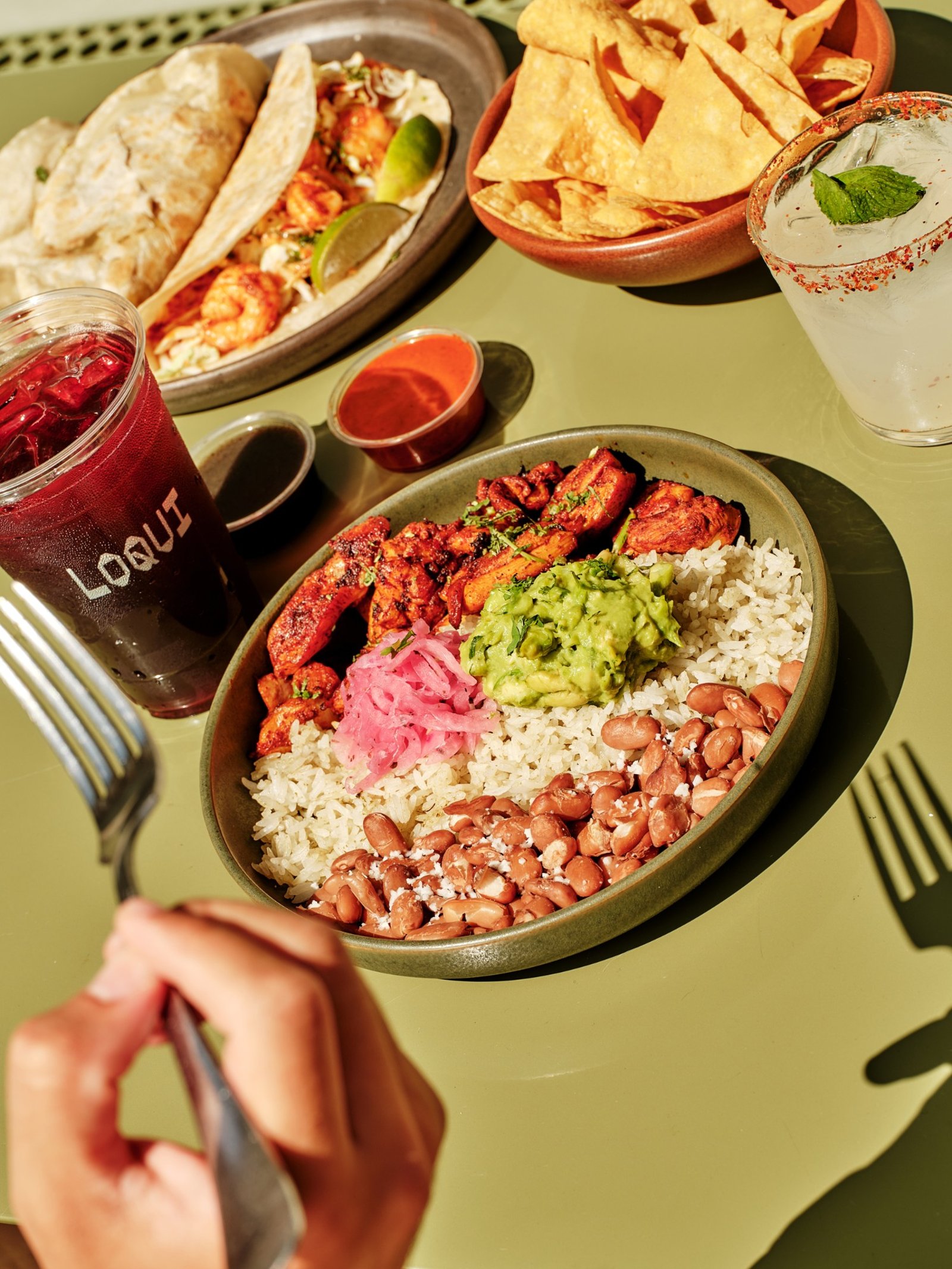 LOQUI chicken bowl with rice, beans, guacamole, shrimp tacos, tortilla chips, and drinks