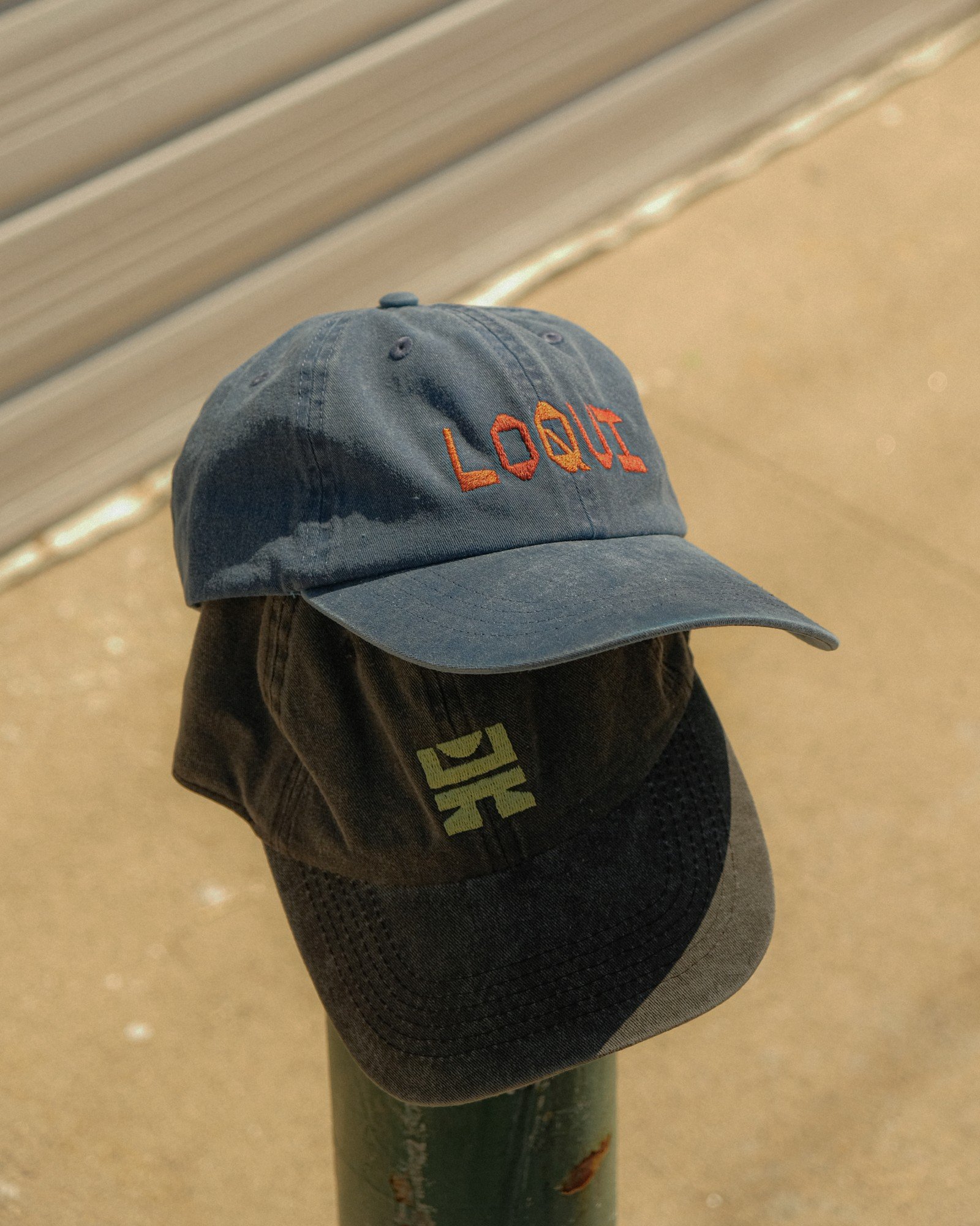Blue and dark LOQUI caps stacked in the sunlight