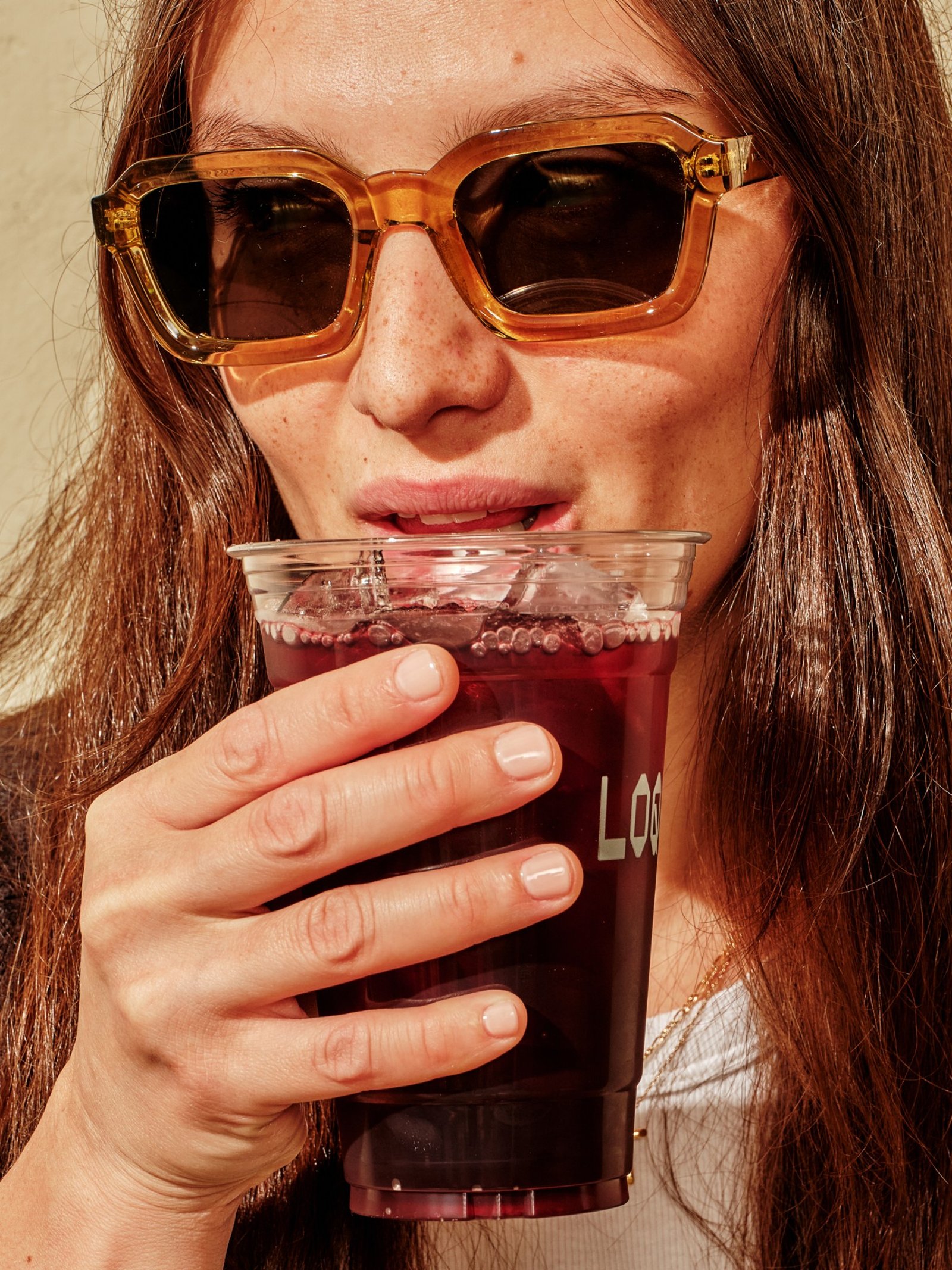 Woman wearing sunglasses enjoying a LOQUI drink