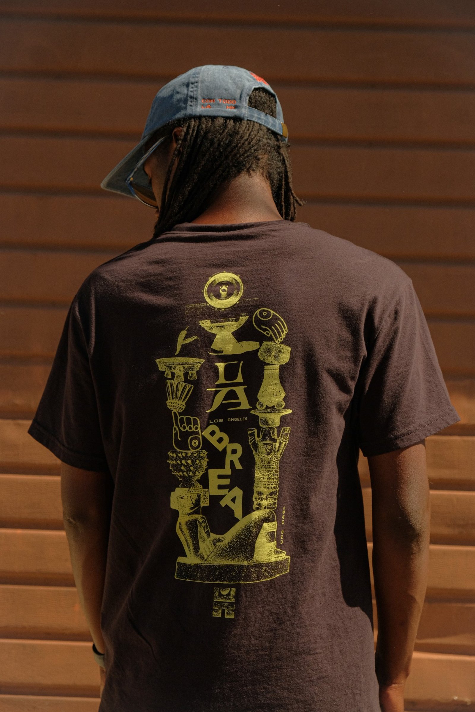 Back of a brown LOQUI T-shirt with a yellow La Brea graphic