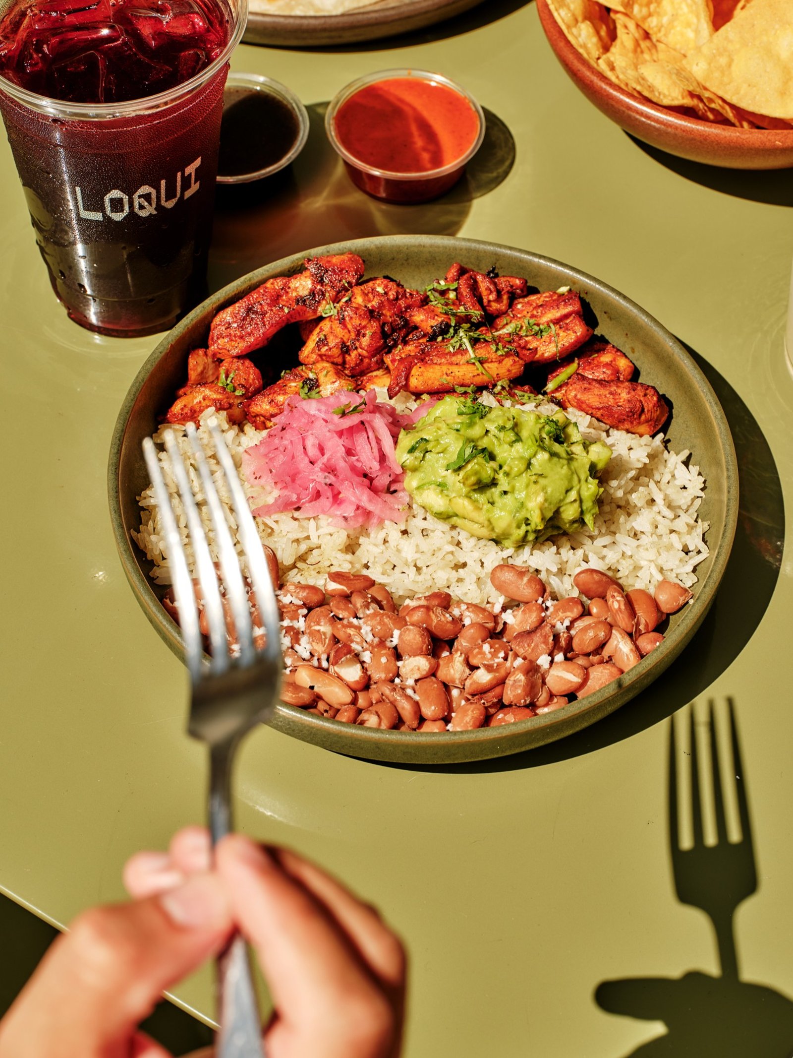 LOQUI chicken bowl with rice, beans, guacamole, and a hibiscus-colored drink