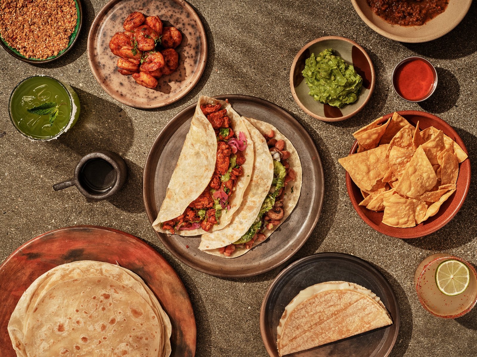 LOQUI tacos, shrimp, guacamole, tortilla chips, and drinks spread across a table