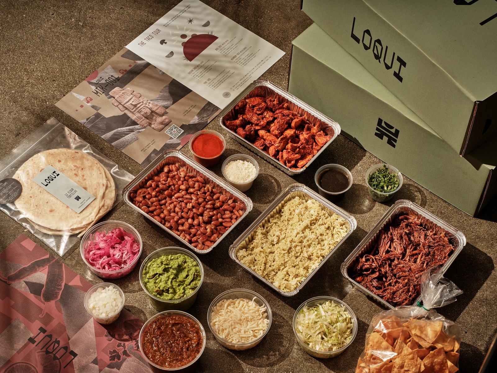LOQUI catering boxes beside taco fillings, rice, beans, tortillas, and toppings