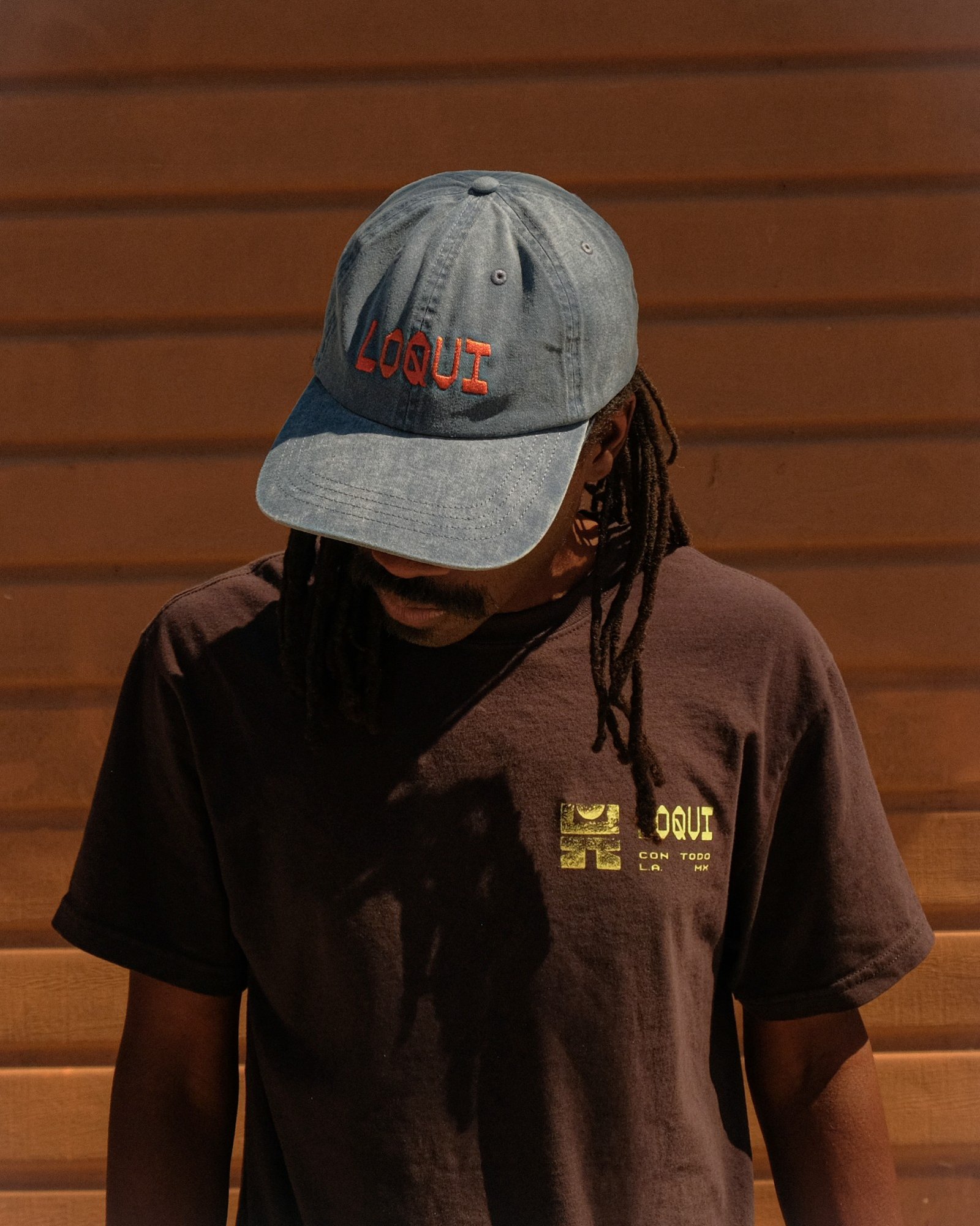 Person wearing a blue LOQUI cap and brown LOQUI T-shirt
