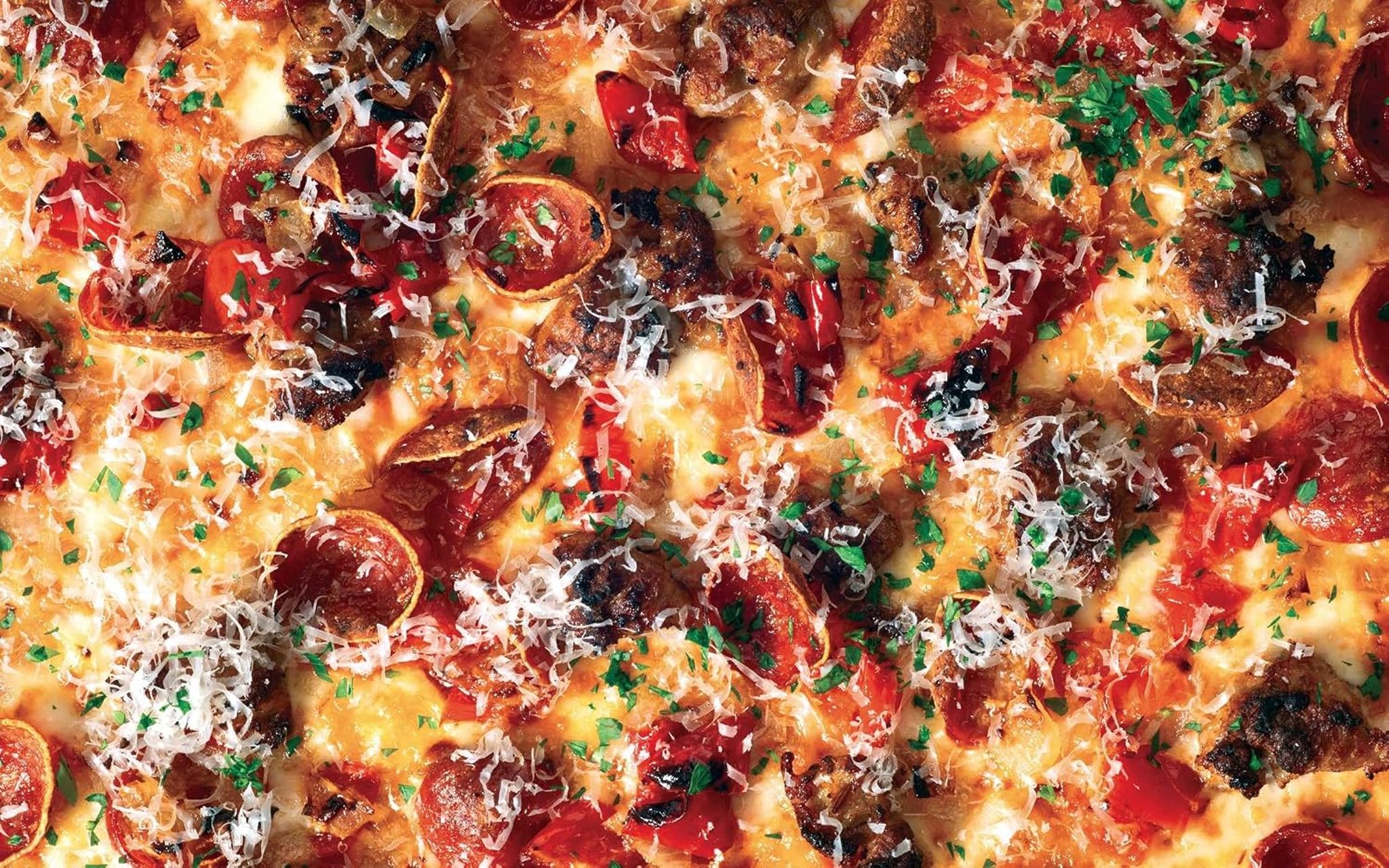Close-up of a Square Pie Guys Detroit-style pizza loaded with pepperoni, sausage, peppers, and grated cheese.