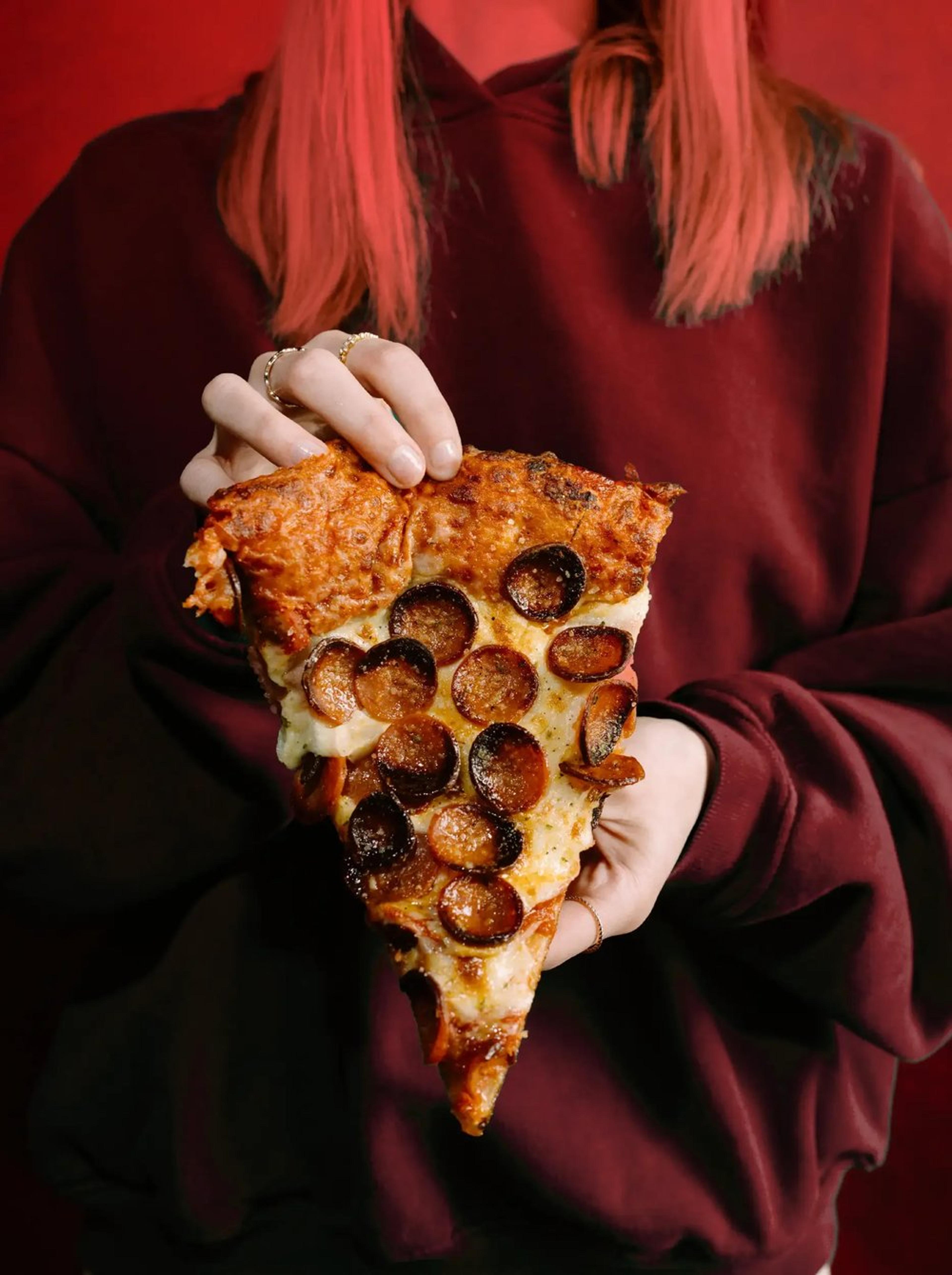 Woman holding a delicious slice of Buffalo style pizza from Picasso's Pizza.