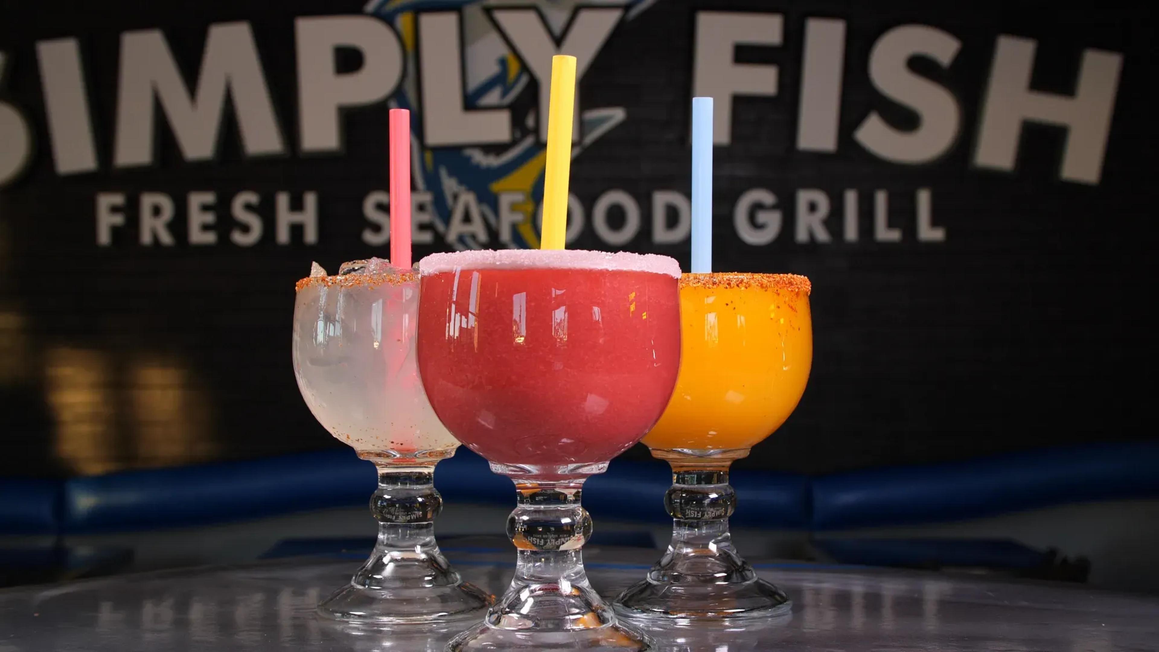Colorful frozen cocktails in front of the Simply Fish Fresh Seafood Grill sign