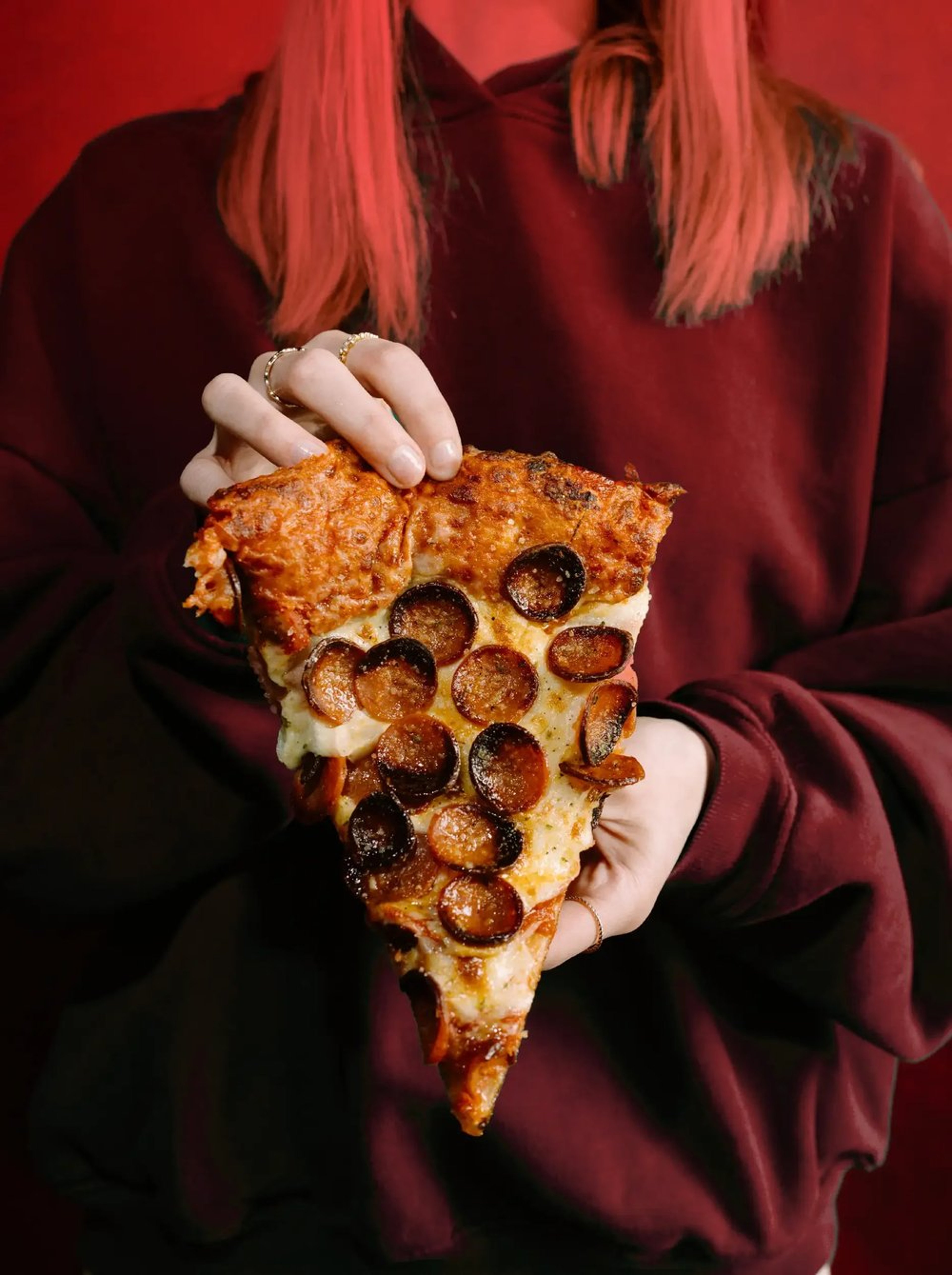 Woman holding a delicious slice of Buffalo style pizza from Picasso's Pizza.