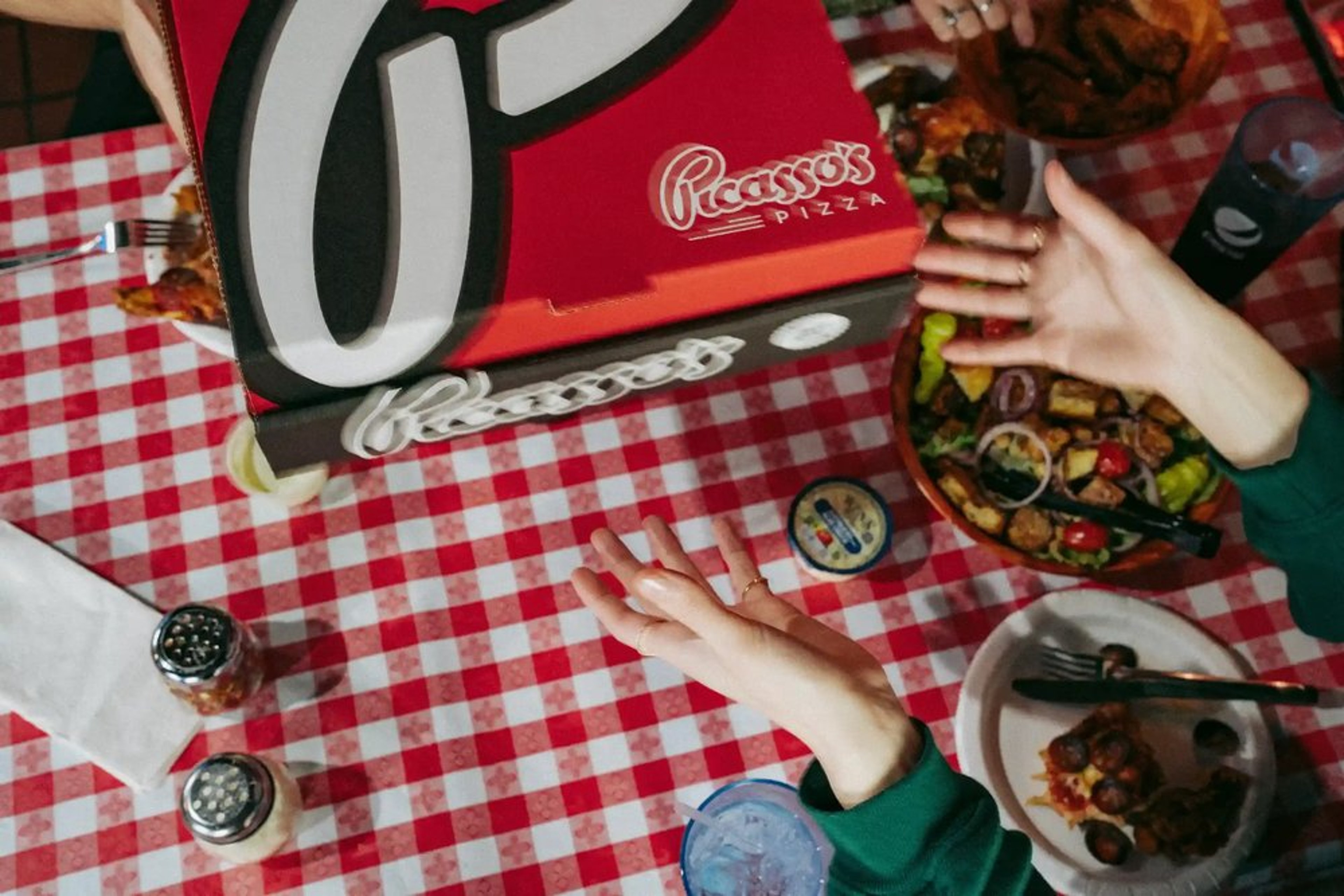Picasso's Pizza box at the restaurant with friends in the background