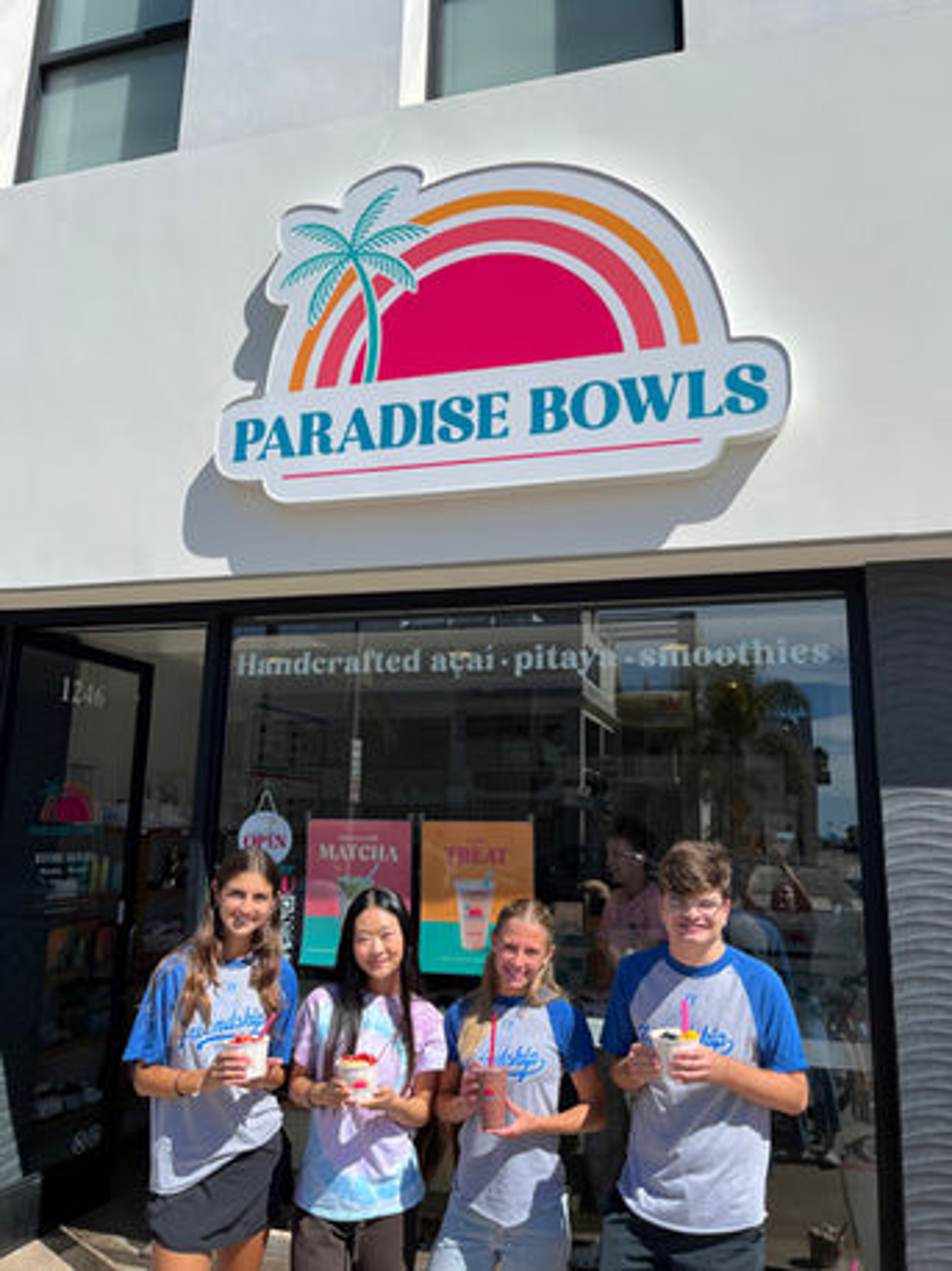 Fundraiser group holding smoothies outside the Paradise Bowls storefront