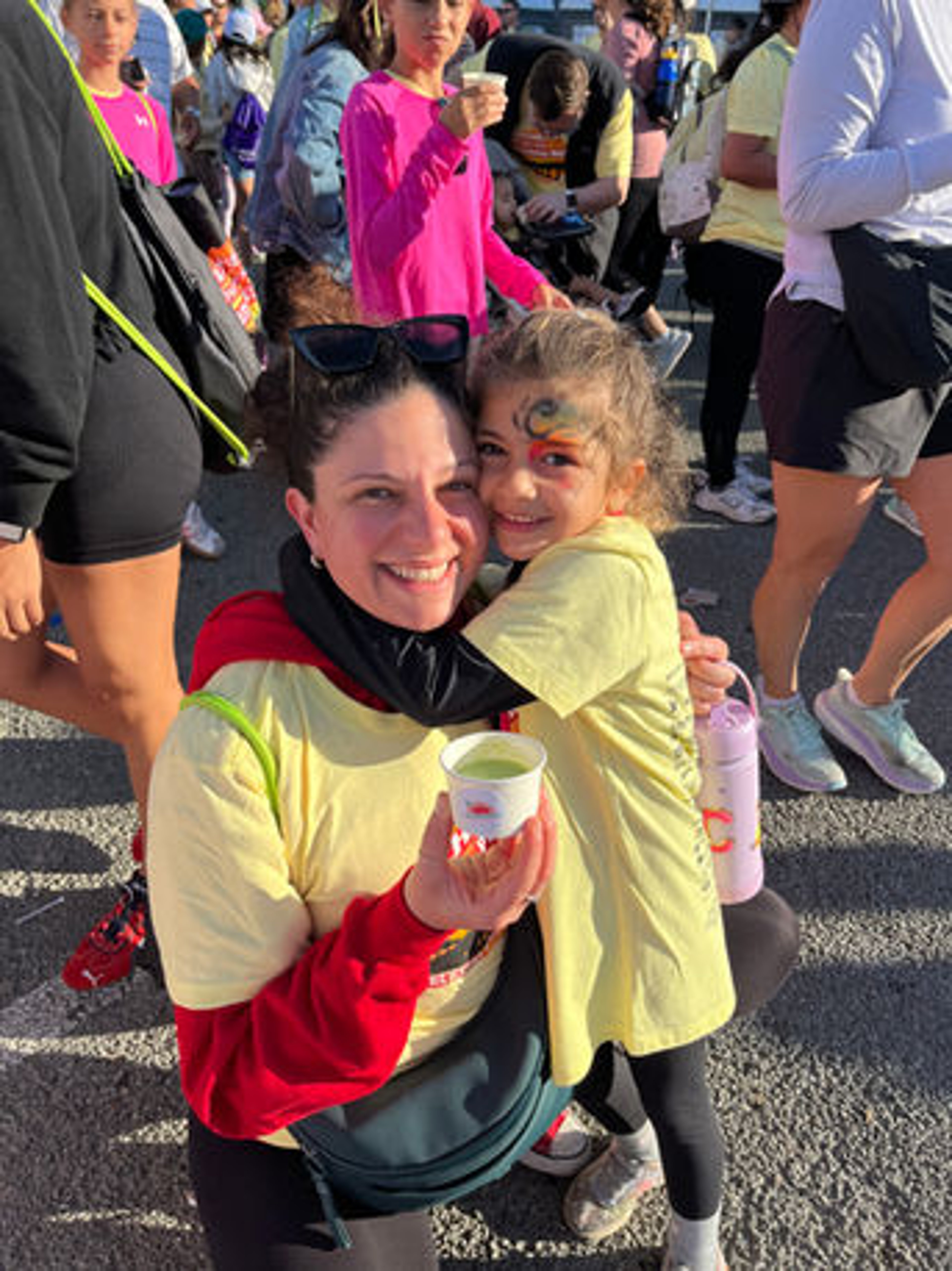 Mother and daughter hugging at a community fundraiser event with a Paradise Bowls cup