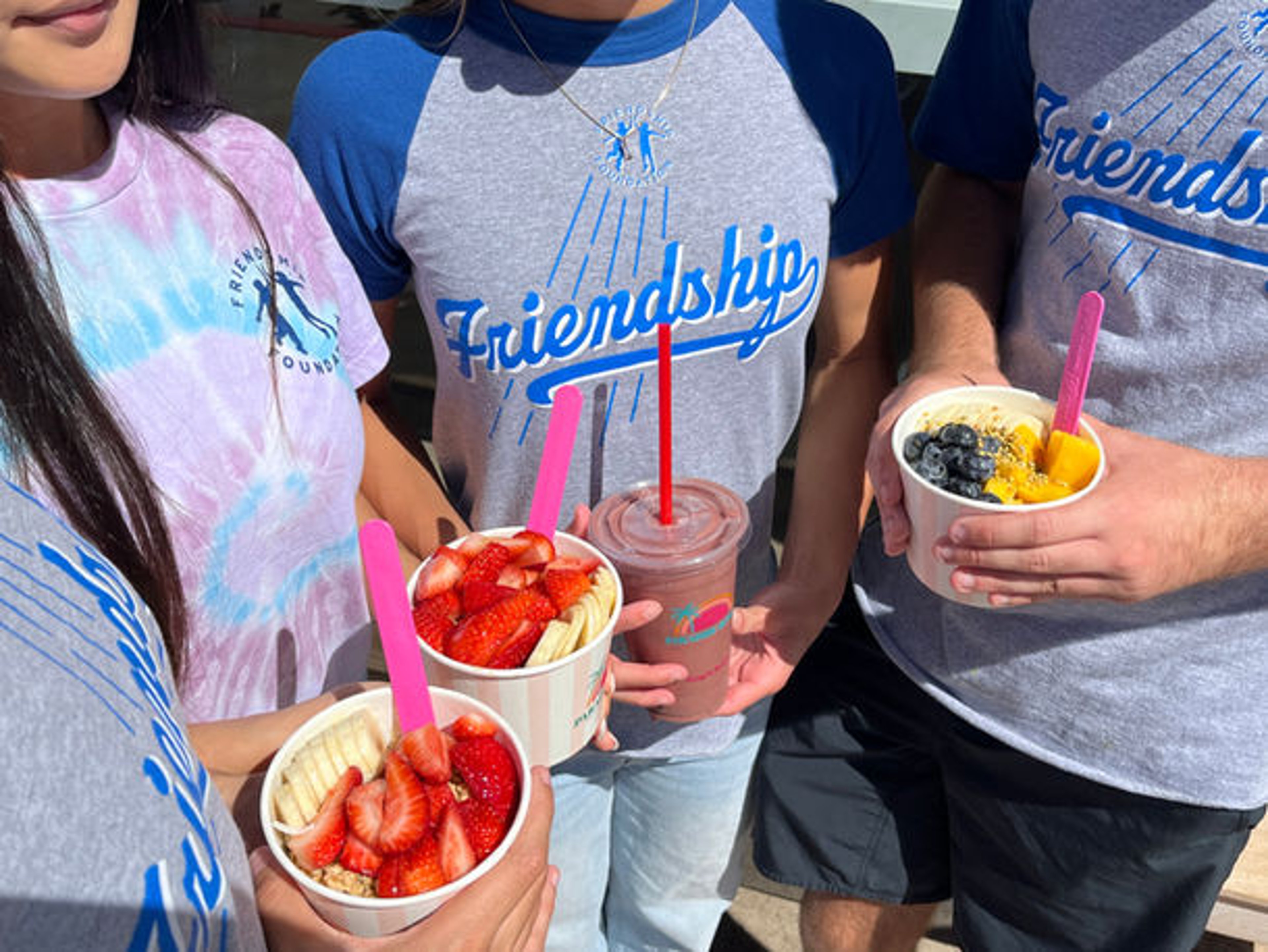 Friendship Foundation members holding acai bowls and a smoothie