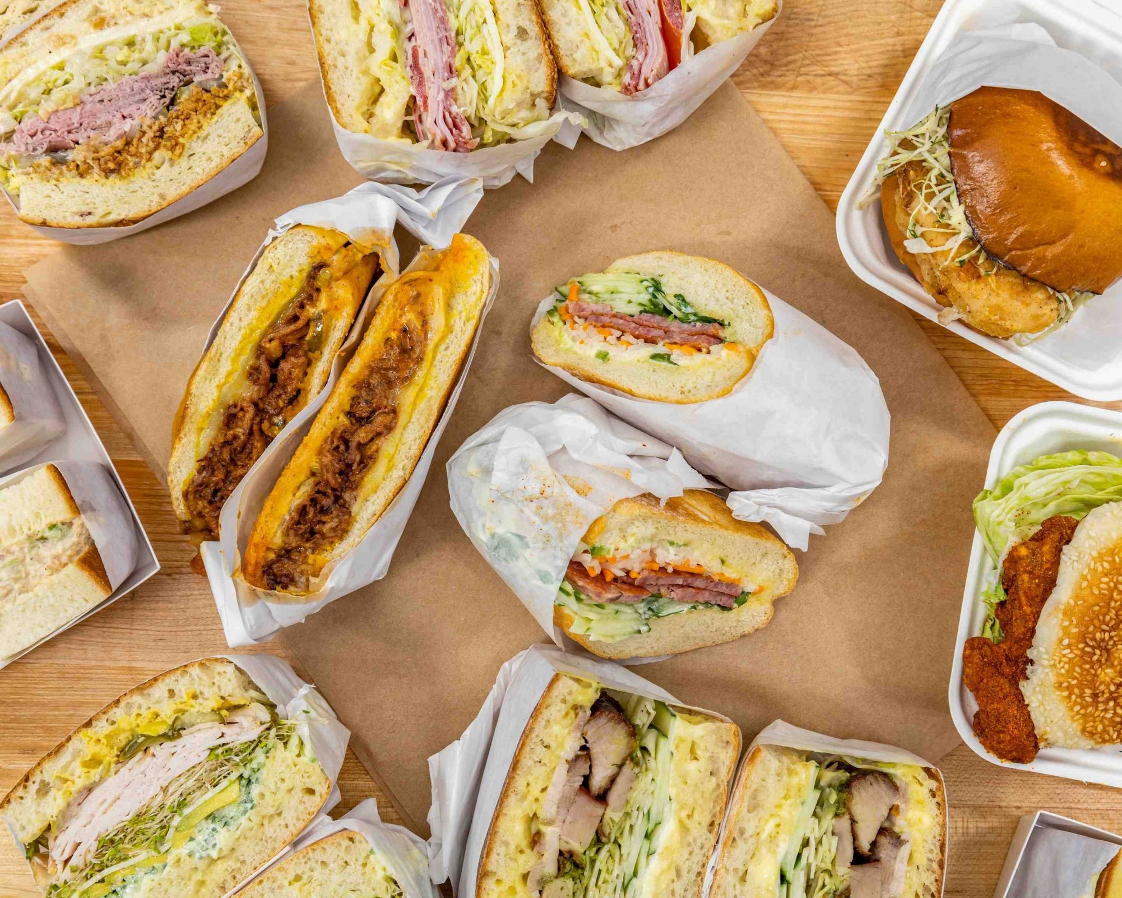 A spread of Ok's Deli sandwiches on a wooden table
