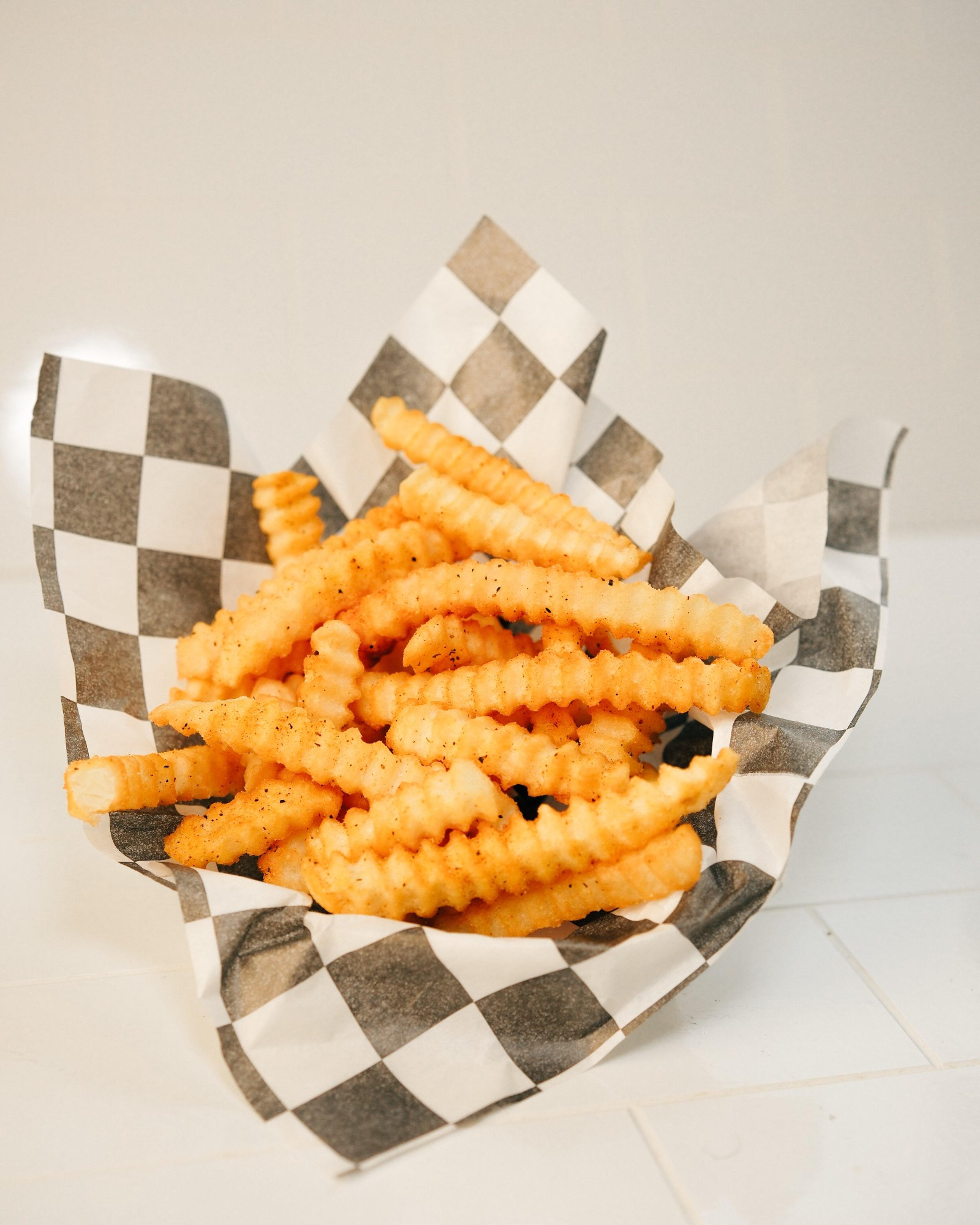 A basket of Big Dave's seasoned crinkle-cut fries on checkered paper